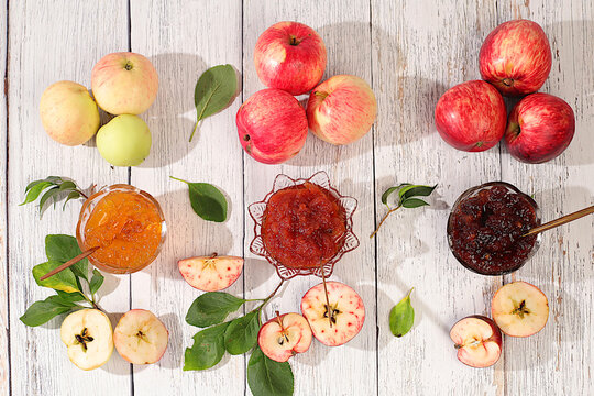 An assortment of preserves, fruit butters and fresh fruit purees arranged on wooden kitchen counter.Fresh apple butter or jam made from various apple varieties. home canning concept, banner