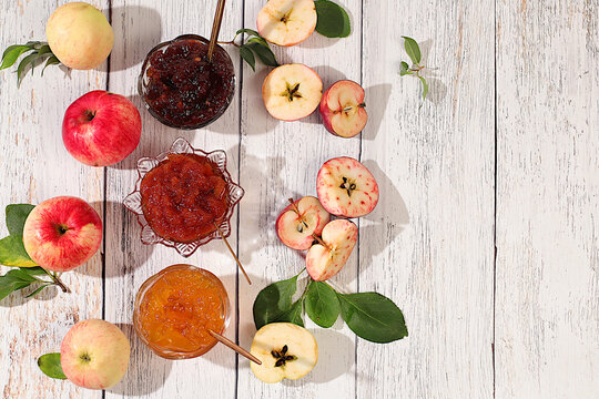 Fresh apple butter or jam made from various apple varieties.An assortment of preserves, fruit butters and fresh fruit purees arranged on wooden kitchen counter. home canning concept, banner