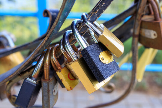 Metal love locks attached to the bridge railing. Brass and iron padlocks fastened by newlyweds in the open air.