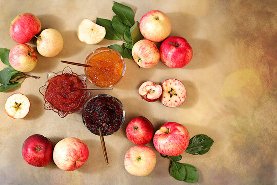 An assortment of preserves, fruit butters and fresh fruit purees arranged on a concrete kitchen counter.Fresh apple butter or jam made from various apple varieties. home canning concept, banner