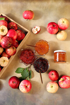 An assortment of preserves, fruit butters and fresh fruit purees arranged on a concrete kitchen counter.Fresh apple butter or jam made from various apple varieties. home canning concept, banner