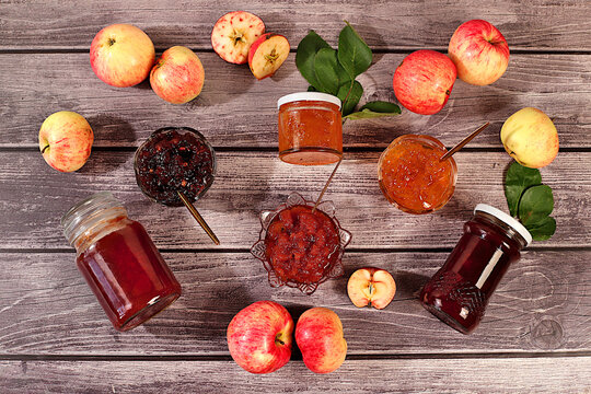 Fresh apple butter or jam made from various apple varieties.An assortment of preserves, fruit butters and fresh fruit purees arranged on wooden kitchen counter. home canning concept, banner