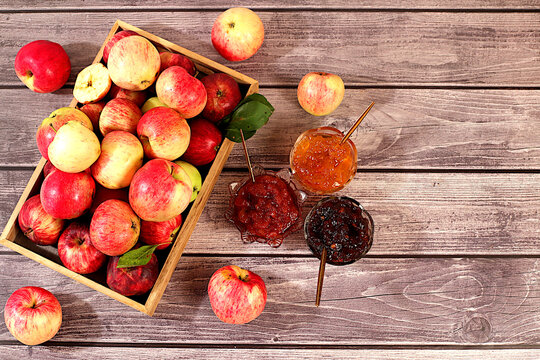 Fresh apple butter or jam made from various apple varieties.An assortment of preserves, fruit butters and fresh fruit purees arranged on wooden kitchen counter. home canning concept, banner