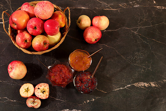 Fresh apple butter or jam made from various apple varieties. An assortment of preserves, fruit butters and fresh fruit purees arranged on a concrete kitchen counter.home canning concept, banner