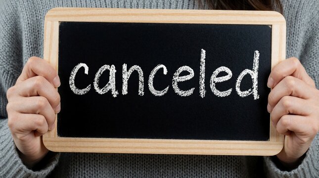 Woman holds chalkboard with Canceled written in chalk. Sign signifies event termination, project halt, or postponed plans. Communication of postponement or stopping.