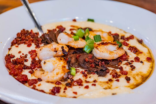 Savory shrimp and grits are served in a white bowl.