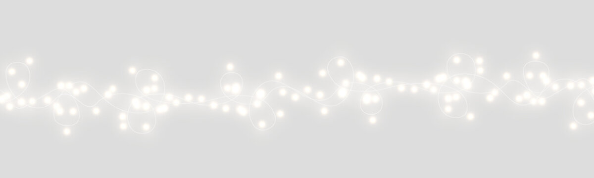 A string of warm white fairy lights stretches horizontally across a dark background. The lights emit a soft, glowing radiance with subtle halos around each bulb.