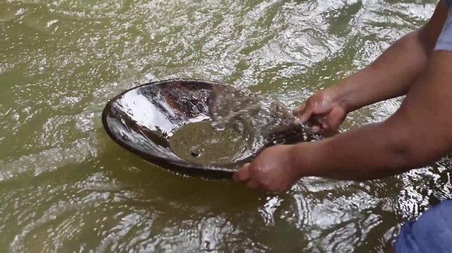 Close up of Latin American woman swirling a batea to separate gold from sediment