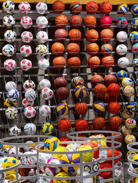 Sports equipment balls of different brands displayed in a modern retail sports store with colorful team game inventory
