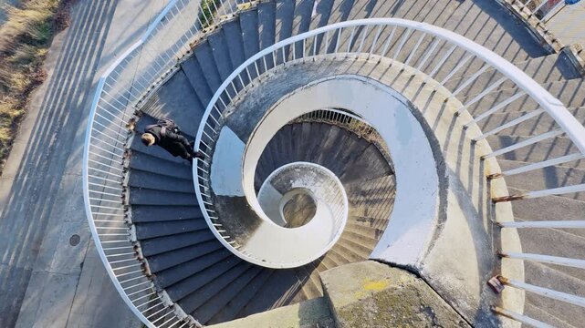 Man Walking Down Spiral Staircase in Warsaw, Poland from Above