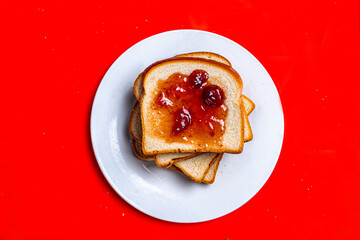 Toast with Berry Jam on White Plate Against Red Background © Dylan