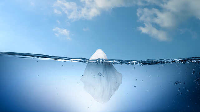 Iceberg floating in water. Concept of difference between hidden and visible parts