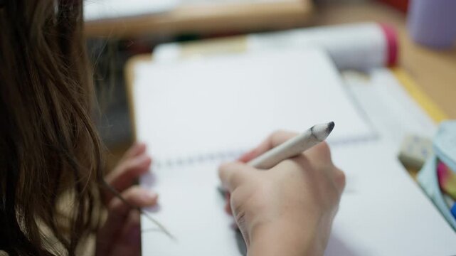 Close up of a student using a paper blending stump to shade a pencil drawing in a sketchbook