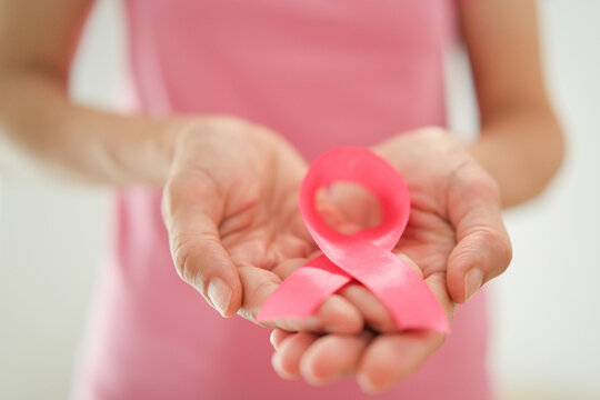 Breast cancer awareness concept with pink ribbon held in female hands