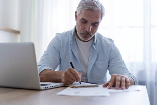 40s business man company manager investor working on computer writing notes
