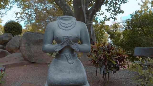 A stone headless statue of a seated female deity, at the Po Nagar Cham Towers in Nha Trang, Vietnam. A headless, kneeling or seated female torso with hands held in a gesture near the chest and wearing