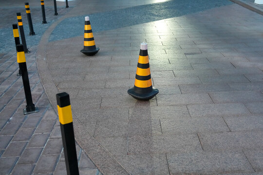 Black and yellow plastic traffic cones standing on access road. Urban safety. Real Photo