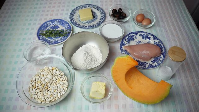Ingredients for chicken, pumpkin and chestnut quiche.
Ingredients for a quiche with pumpkin, chestnuts, chicken and thyme are arranged on a table.