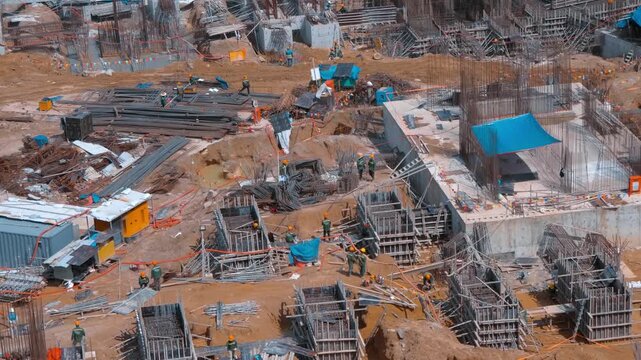 A large-scale construction site with dense rebar cages, formwork systems and support structures for heavy concrete pouring, scaffolding, workers in safety gear on the foreground