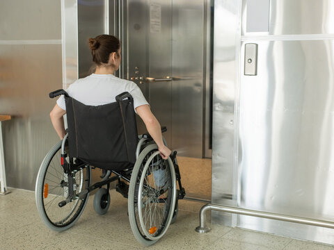 A Caucasian woman in a wheelchair uses an elevator.