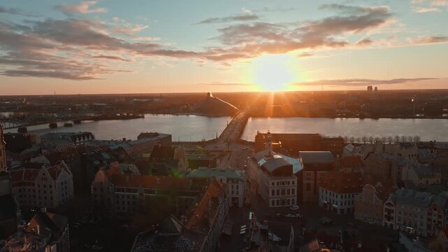 Riga old town, St Peters tower and Daugava at sunset from drone, Latvia. Aerial shot flying over historic rooftops of Riga, Latvia.