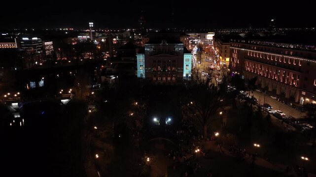 Projection mapping on National Opera facade at night from drone, Riga. Aerial shot of colorful light art projected on the opera house in Riga, Latvia, during light festival with crowds.