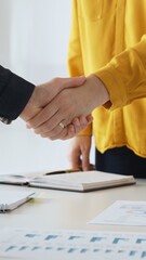 Plakat Business partners shaking hands after successful meeting in office while another person is clapping hands over financial documents, laptop and notebook