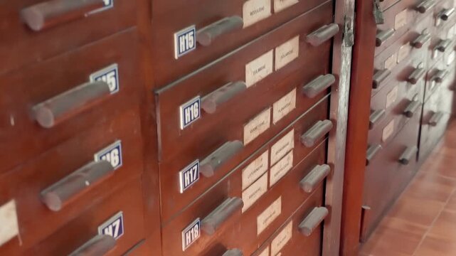 Vintage wooden card catalog features dozens of small drawers, used for organizing index cards. Closeup. Shot in motion