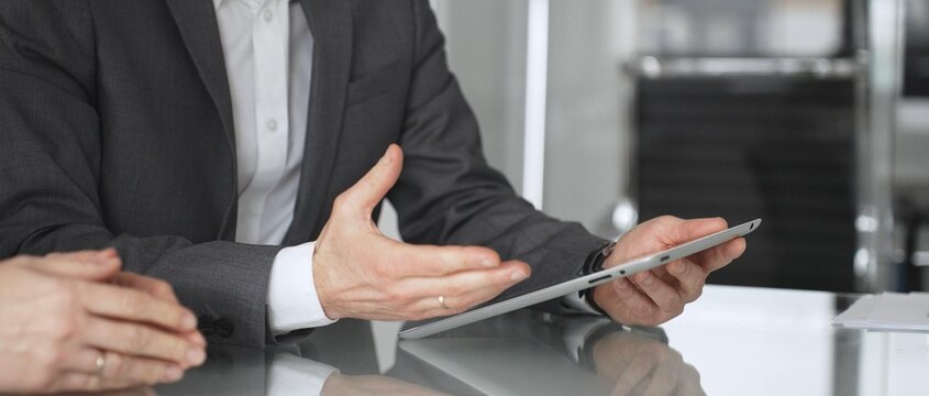 Business colleagues collaborating on a digital tablet, discussing data and financial insights during an office meeting, symbolizing technology integration and professional partnership, close up
