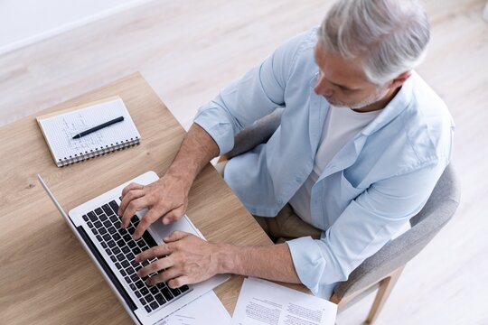 Top view of 40s man sitting at desk with laptop computer at home office