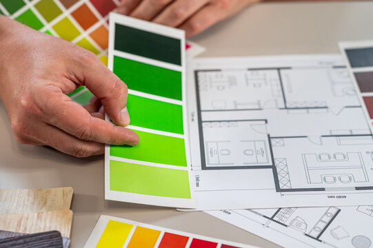 Close up of Interior Designer Hands Selecting Color Swatch Palette Over Architectural Sketch