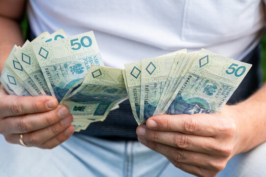 Male Hands Holding and Counting Stack of Polish 50 Zloty Currency Bills for Business Finance