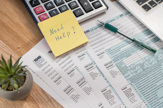 Close up of US Tax Form 1040 with Need Help Note and Calculator for Financial Advisory Concept