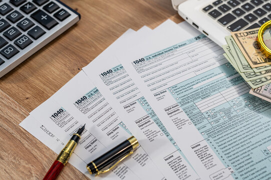 Tax Return Document 1040 Form with American Dollars Stack and Calculator on Desk for Filing