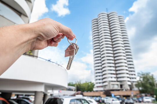 Male Hand Holding House Keys on Palm in Front of Apartment Building Construction Site Concept