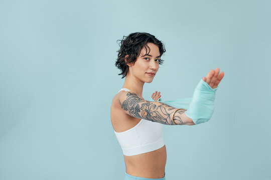 Studio shot of a young woman practicing with a stretching band over a blue backdrop