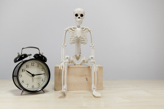 Skeleton Figure Waiting Beside Alarm Clock With Copy Space