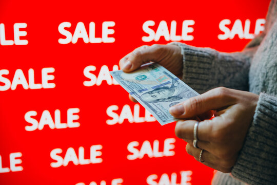 Person holding US dollar banknotes during sale shopping.