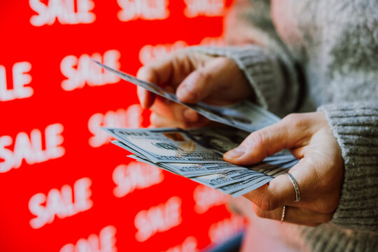 Person holding US dollar banknotes during sale shopping.