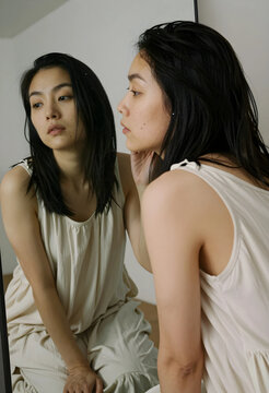 Self reflection and mental health, young woman looking at her mirror image with introspection and authentic beauty in a calm home environment