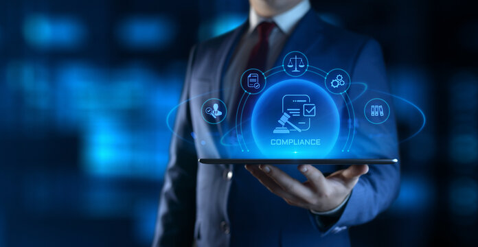 Businessman holding tablet with compliance icons on screen - business and regulations concept