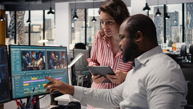 Team of videographers uses AI software tools to edit video on a PC in a studio office, applying neural networks to cinematic transitions and montage clips.
