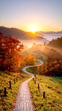 Herbstlicher Bergweg in goldener Alpenlandschaft mit Nebel