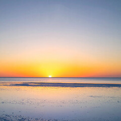 Fototapeta premium A breathtaking sunset over a salt flat, casting golden light on the reflective surface. This peaceful, minimal landscape features no people, evoking serenity and hope for travel and wellness.