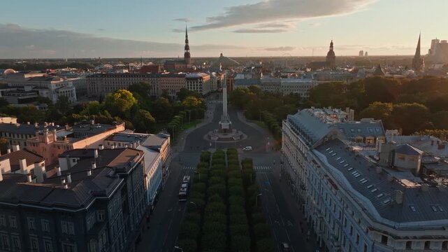Freedom Monument Milda and boulevards toward old town from rising drone, Riga. Aerial shot rising behind the Liberty statue in Riga, Latvia, over tree alleys.