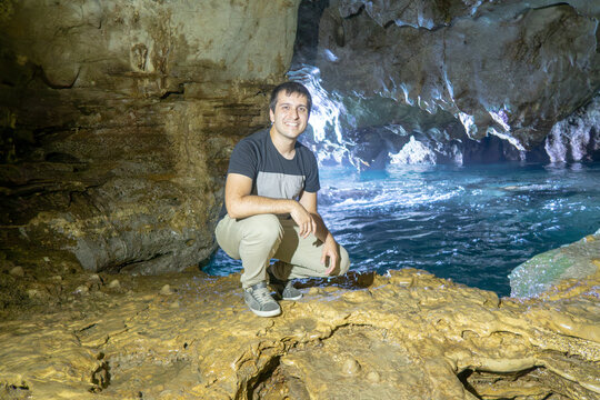 Man exploring Cobijero cave with blue water in Asturias