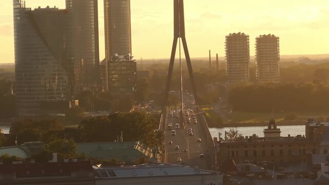 Vansu bridge pylon and traffic in golden haze from drone, Riga. Telephoto aerial shot of cars crossing the cable stayed bridge over Daugava in Riga, Latvia.