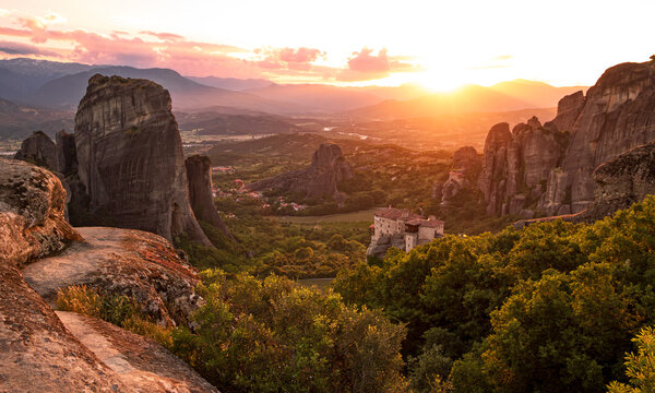 Landscape view of the Meteora rock formations and monasteries in the Pindos Mountains of Greece during sunset.