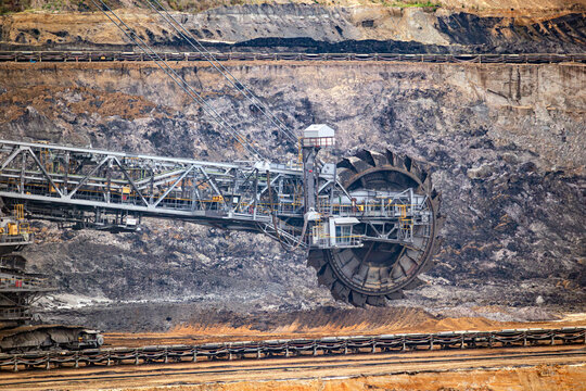 Close-up view of the massive bucket wheel of a bucket wheel excavator operating deep inside a brown coal open-pit mine.