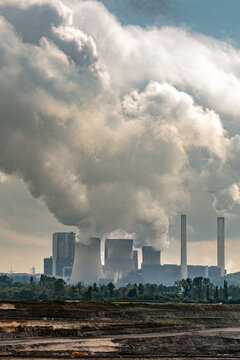 Large brown-coal power plant with tall chimneys and huge smokestacks rising against the sky. Part of coal-fired electricity generation, fossil fuel use and energy production.